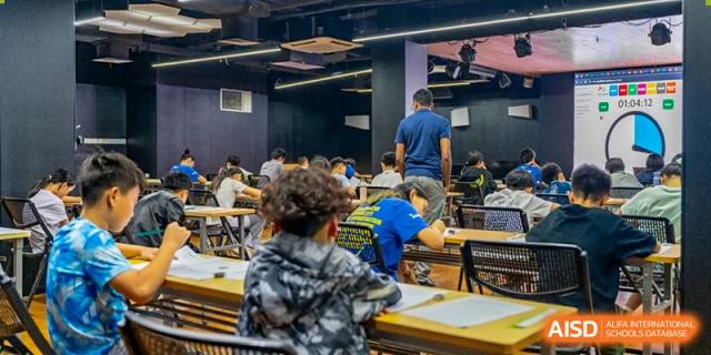 A teacher at QSI International School of Shenzhen assisting young students with their work at their desks in a classroom.