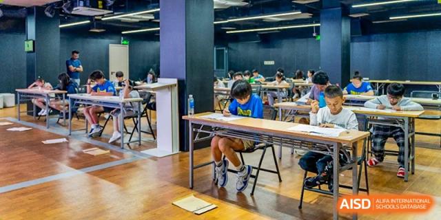 A student from QSI International School of Shenzhen focused on their work while sitting at a desk in a classroom.
