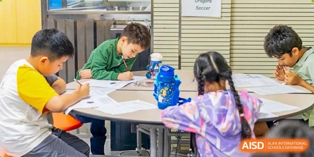Young students at QSI International School of Shenzhen working together on a project or assignment at a table.