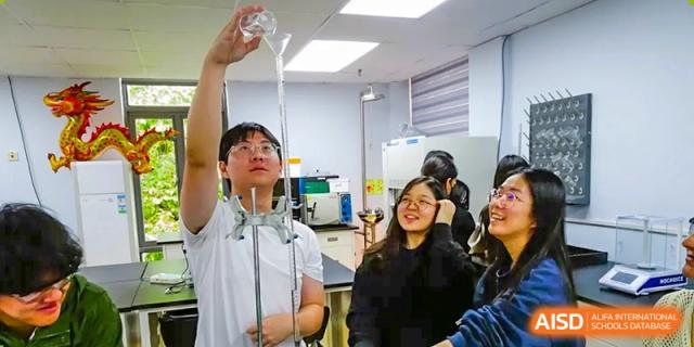 Students at QSI International School of Shenzhen participating in a science experiment, watching water pour into a device or container.