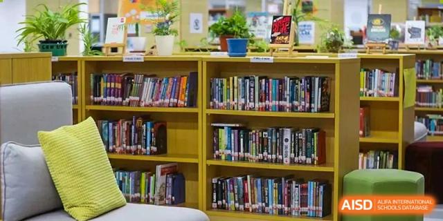 A well-stocked wooden bookshelf filled with various books in the QSI International School of Shenzhen library.