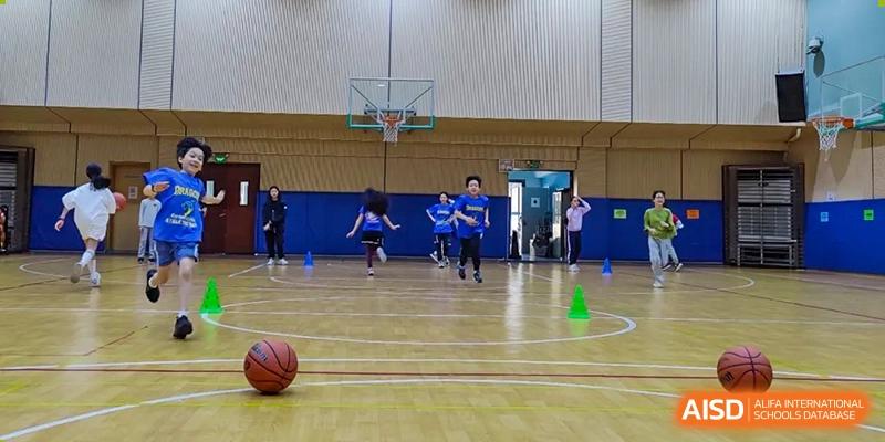 Students running drills on the indoor basketball court at QSI International School of Shenzhen during practice or a physical education class.