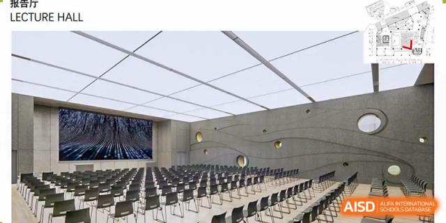 The spacious and modern auditorium or assembly hall at QSI International School of Shenzhen with rows of black chairs set up for an event.