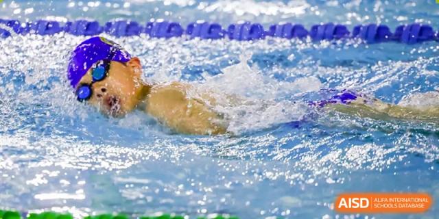 A close-up shot of a student from QSI International School of Shenzhen performing the crawl stroke while swimming in a pool.