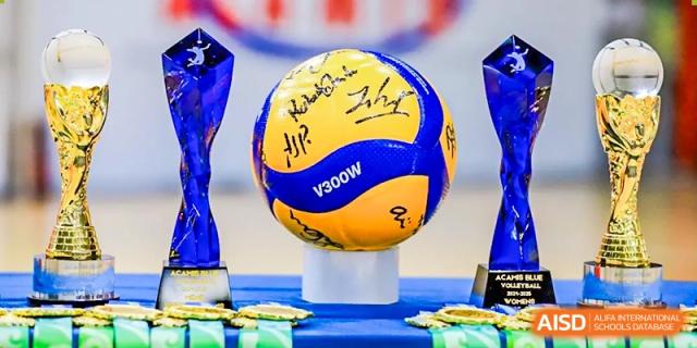 A close-up of a signed blue and yellow volleyball trophy displayed on a pedestal, representing an athletic achievement at QSI International School of Shenzhen.