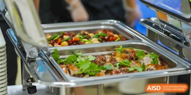 A close-up shot of a buffet tray filled with a fresh salad or cooked vegetables, part of the meal service at QSI International School of Shenzhen.