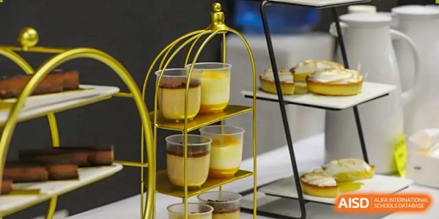 Elegant individual desserts in glasses displayed on a gold tiered stand at an event or meal at QSI International School of Shenzhen.