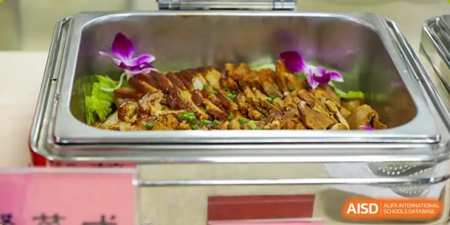 A buffet tray filled with slices of crisp, roasted pork or chicken, a main course option at QSI International School of Shenzhen.