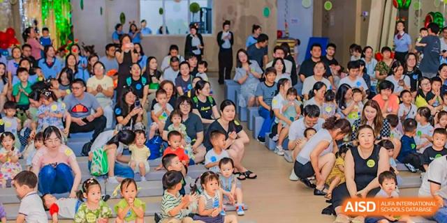 A large group of young students and parents gathered closely on the floor to watch a presentation or performance at Suzhou Foreign Language School.