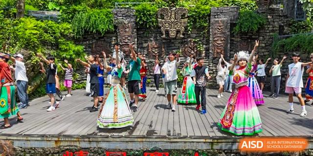 Students in traditional costume performing an outdoor group dance on a wooden path near an ancient structure at Suzhou Foreign Language School.