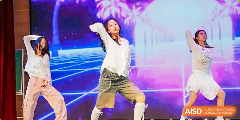 A student striking a dynamic pose on stage during a modern dance performance with a brightly lit background at Suzhou Foreign Language School.