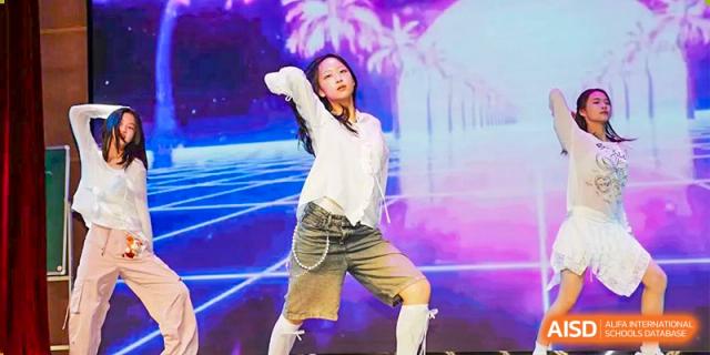 A student striking a dynamic pose on stage during a modern dance performance with a brightly lit background at Suzhou Foreign Language School.