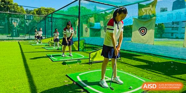 A student practicing golf in an outdoor netted driving range area at Suzhou Foreign Language School.