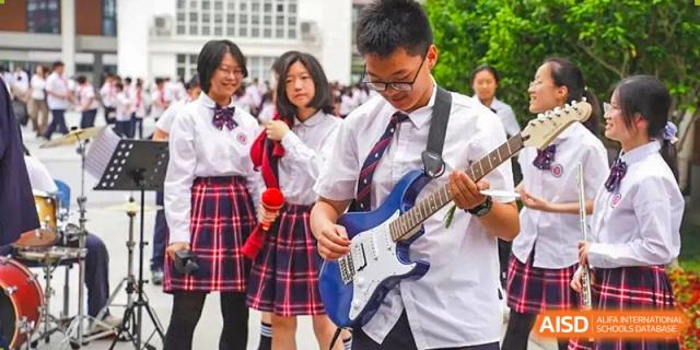 A student playing an electric guitar, performing with a group of students in school uniforms at Suzhou Foreign Language School.