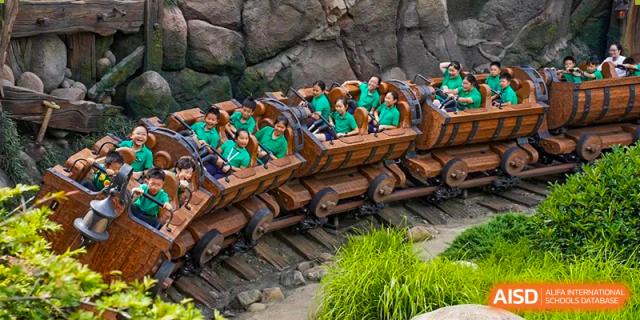 Students and teachers riding a roller coaster or amusement park ride together during a fun school outing organized by Suzhou Foreign Language School.