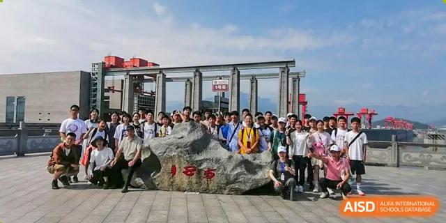 A large group of students and teachers gathered for a photo next to a large stone landmark during a field trip or excursion organized by Suzhou Foreign Language School.