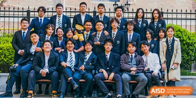 A large group of students in dark suits and ties posing for a formal class or club portrait at Tianjin Farragut School.