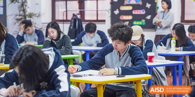 A student focused on an individual written test or in-class assignment at a desk in a classroom at Tianjin Farragut School.