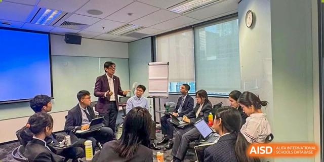 Students and faculty attending a formal business or lecture-style meeting led by an adult presenter in a professional setting at Tianjin Farragut School.