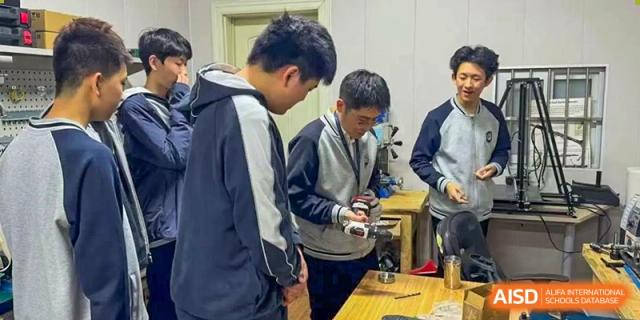A small group of male students working together and discussing a technical device or circuit in a workshop or class at Tianjin Farragut School.