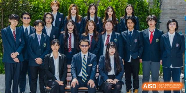 A large group of students and a male teacher in suits and ties posing for a formal portrait at Tianjin Farragut School.