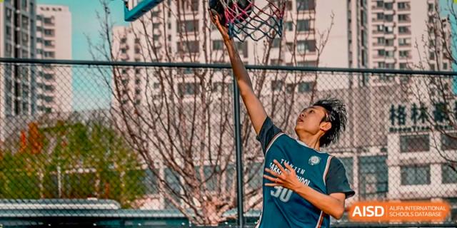 A student in a blue jersey shooting a basketball towards the hoop during a practice or game at Tianjin Farragut School.