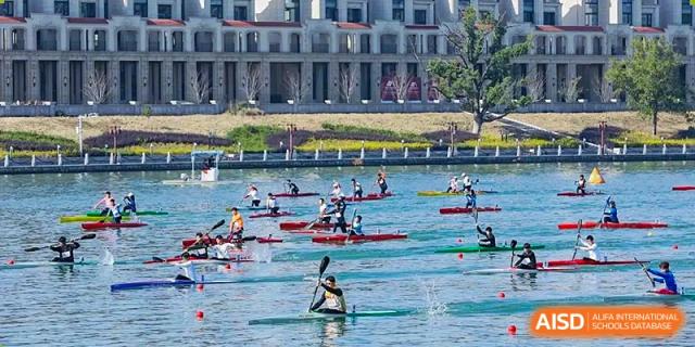 Students paddling kayaks or canoes in the water during an outdoor watersports competition or training session at Tianjin Farragut School.