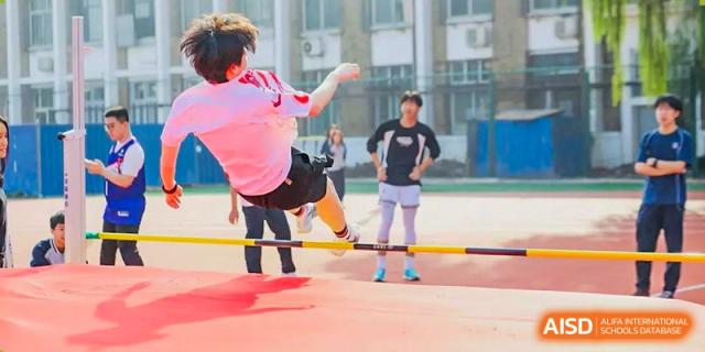 A student performing a powerful high kick or martial arts move outdoors while other students observe during physical training at Tianjin Farragut School.