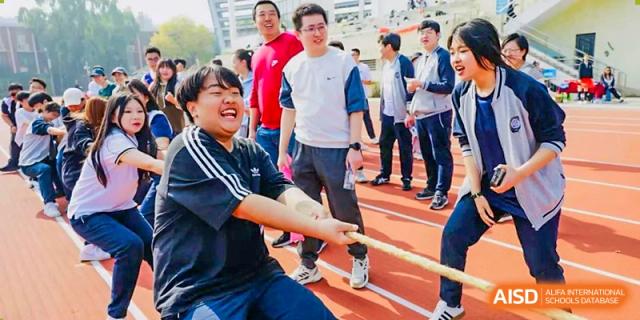A group of students and adults participating in an outdoor tug-of-war game during a fun sports day event at Tianjin Farragut School.