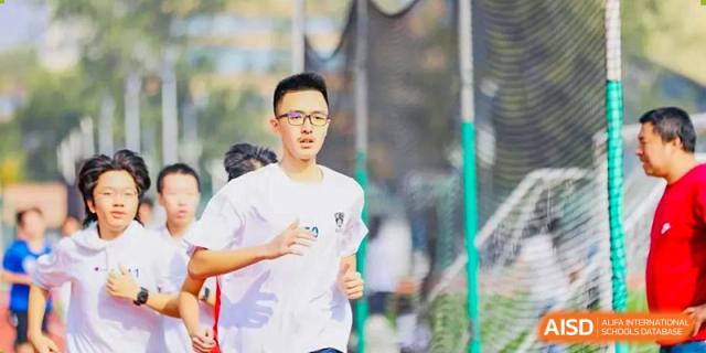 A student in a white t-shirt running outdoors during a cross-country event or physical training at Tianjin Farragut School.