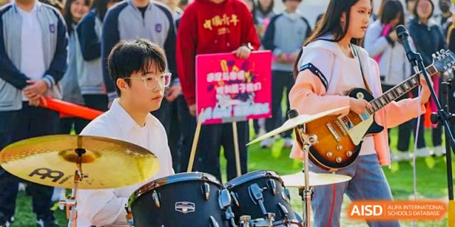 A student playing the drums on stage during a musical performance or band practice at Tianjin Farragut School.