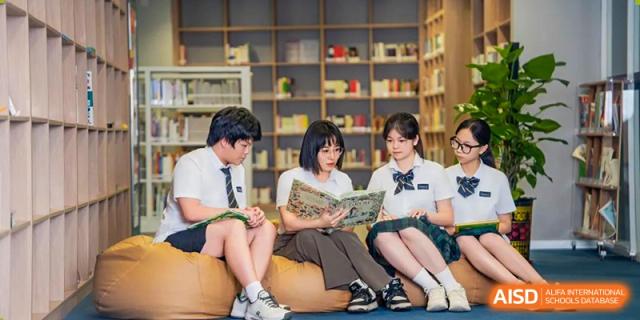 Three high school students in uniform are reading books together on beanbag chairs in a library at Ardingly College Zhongshan (ACZS), highlighting collaborative learning and comfortable spaces.