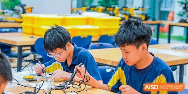 A close-up of a student soldering electrical components in a science or technology workshop at Ardingly College Zhongshan (ACZS), highlighting hands-on technical and vocational training.