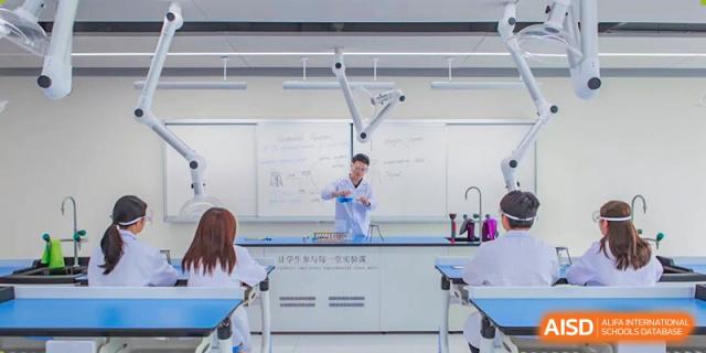 A teacher performs a chemistry or science demonstration in a lab with observing students in the spacious and modern facilities of Ardingly College Zhongshan (ACZS), showing practical science.