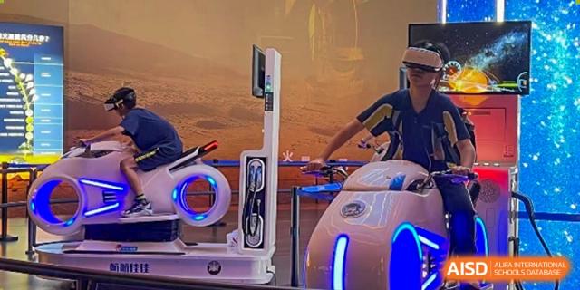 A detailed shot showing an interactive robotics or technology display at Ardingly College Zhongshan (ACZS), where a student is engaging with futuristic, white and blue glowing equipment.