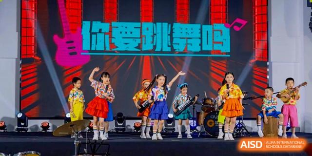Students are energetically performing with musical instruments as a band on stage with bright lights and Chinese text at Ardingly College Zhongshan (ACZS), highlighting music education.