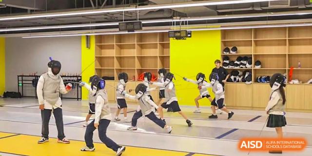 Students in protective gear are practicing fencing maneuvers in a gymnasium, highlighting the specialist sports and physical education offered at Ardingly College Zhongshan (ACZS).