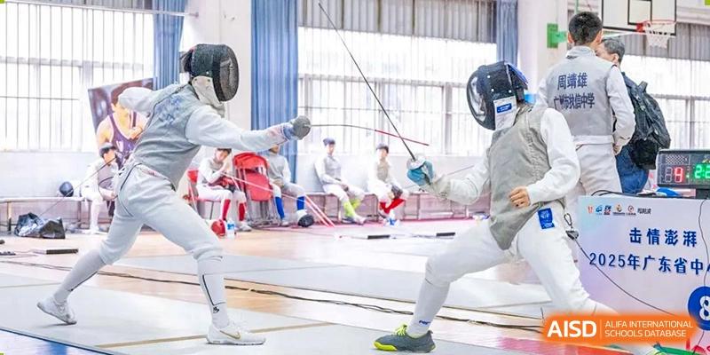 Two students dressed in full protective gear are engaged in a fencing bout in a brightly lit gymnasium at Ardingly College Zhongshan (ACZS), demonstrating diverse and specialized sports.