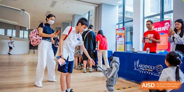 A student is interacting with a robotics display or project in a modern, open-plan learning area at Ardingly College Zhongshan (ACZS), showcasing hands-on technology education.