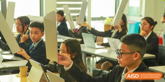 Students in a classroom hold up white boards to participate in an interactive learning activity at Korea International School in Shenzhen.