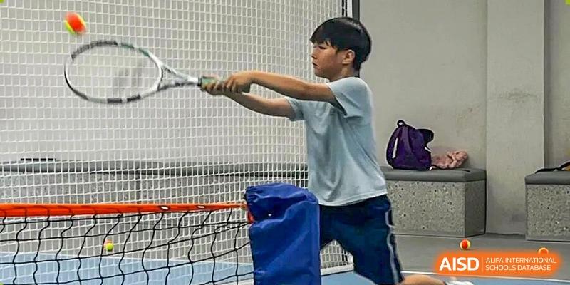 A young boy focuses on his form while practicing his swing with a racquet on a court at Korea International School in Shenzhen.