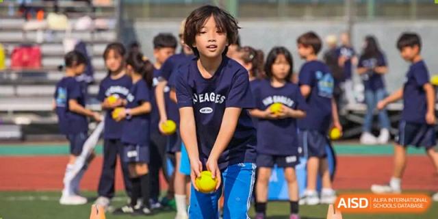 A group of students in navy blue uniforms play with yellow balls during physical education at Korea International School in Shenzhen.