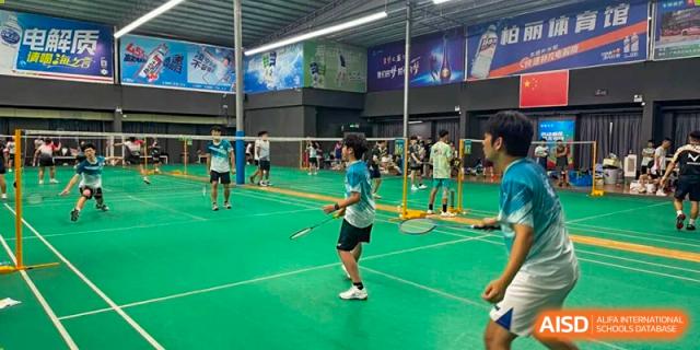 Multiple students participate in a badminton tournament on several indoor courts at Korea International School in Shenzhen.