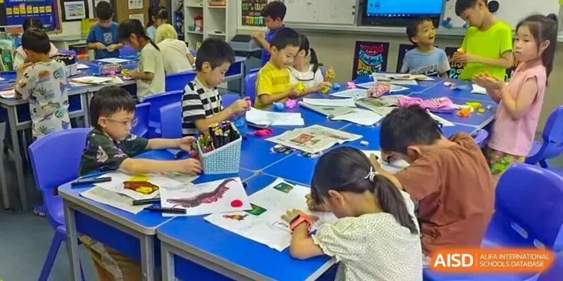 Elementary students sit at blue desks focused on an art and coloring project in a classroom at Korea International School in Shenzhen.