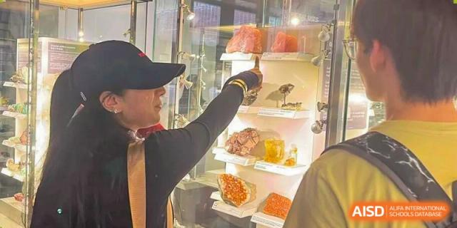 A student points to various geological rock and mineral specimens displayed in a glass exhibit case at Korea International School in Shenzhen.