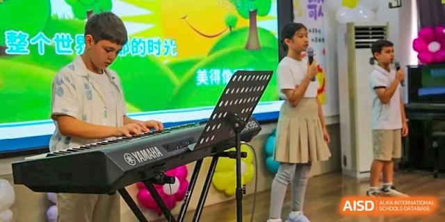 A student stands at a microphone next to a Yamaha keyboard during a musical presentation at Korea International School in Shenzhen.