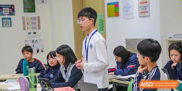 A young student in a formal uniform standing to deliver a presentation to his classmates at BASIS International School Wuhan.