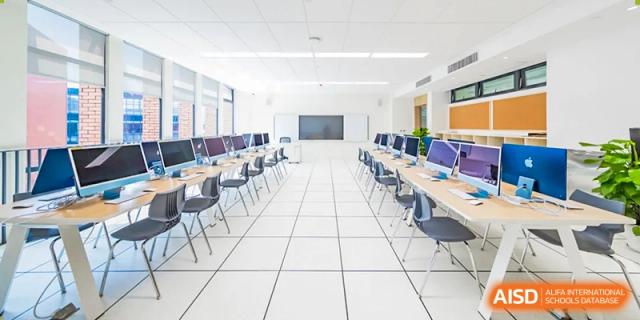 A modern computer lab with rows of Apple iMacs and ergonomic seating for student use at BASIS International School Wuhan.