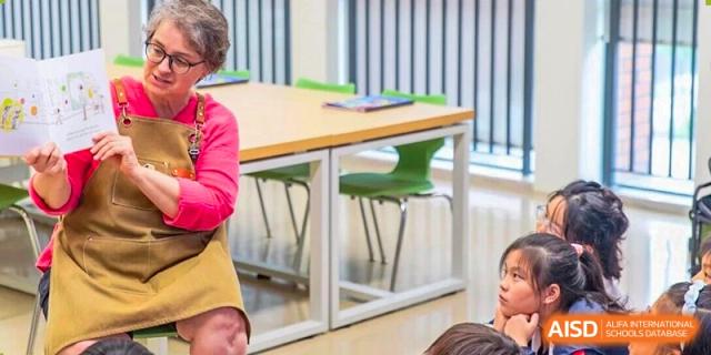 A teacher engaging with students in a brightly lit, modern classroom setting at BASIS International School Wuhan.