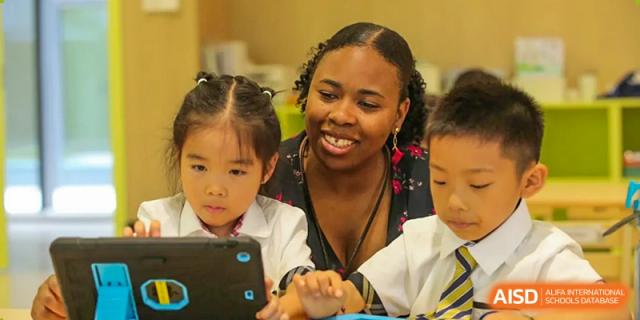 An educator helping young students interact with digital learning tools in an early years setting at BASIS International School Wuhan.
